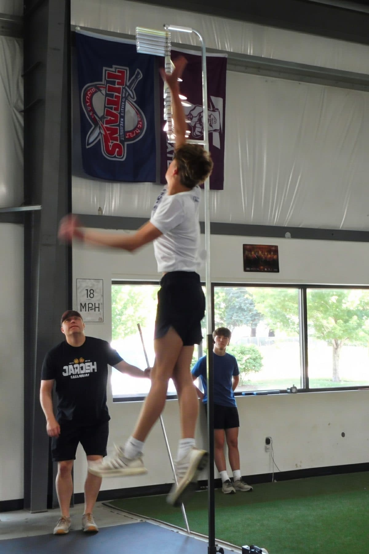 An athlete jumps toward the vanes during a vertical-jump test as a Jarosh Performance coach watches.