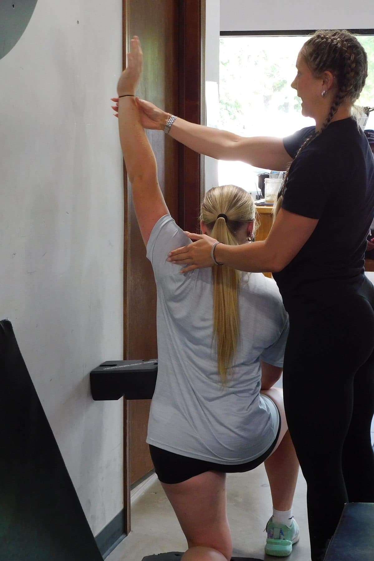 A Jarosh Performance coach guides an athlete’s arm and shoulder position during a mobility drill.