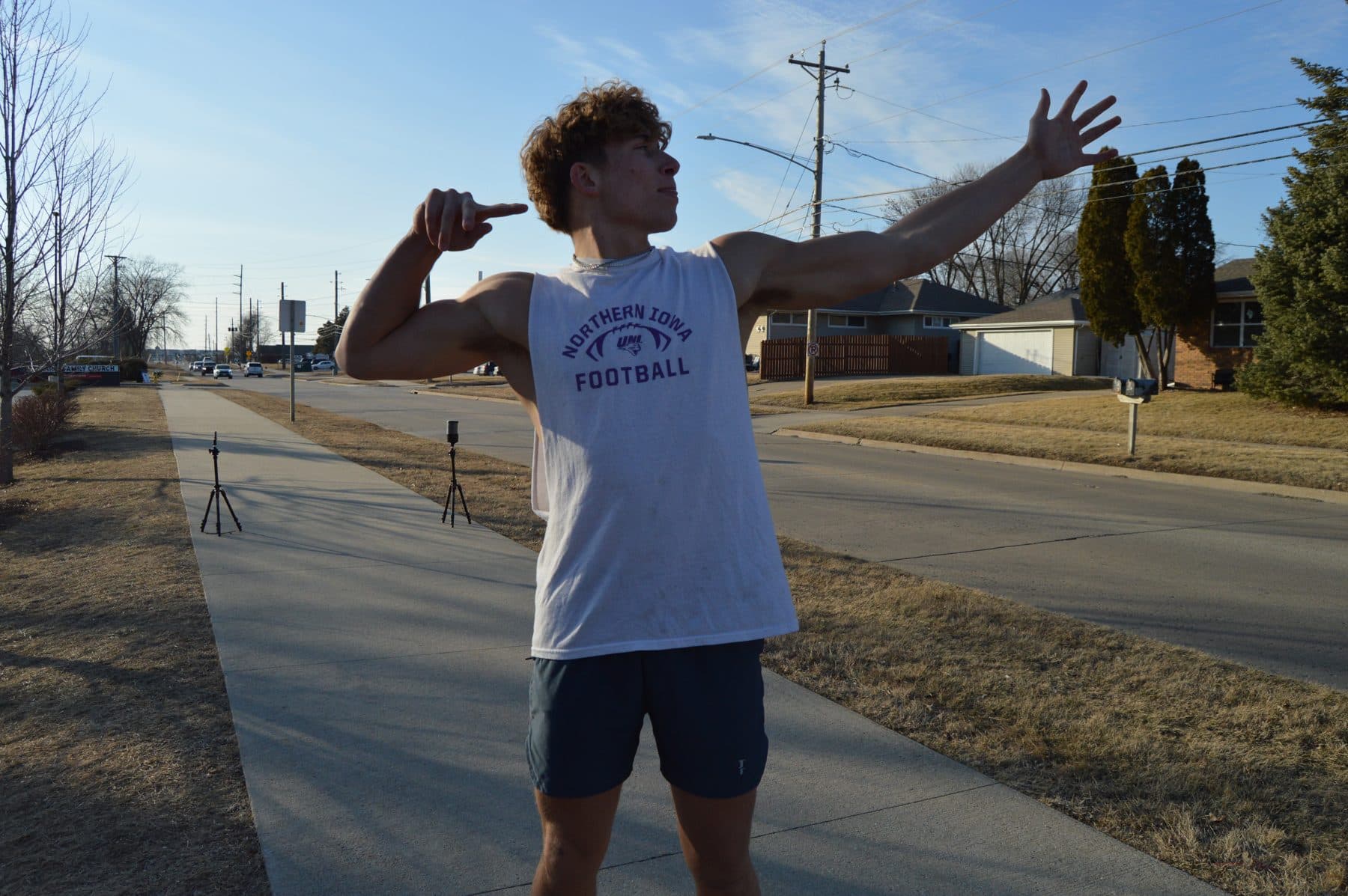 An athlete strikes a pose on the outdoor sprint course, with timing gates set up behind.