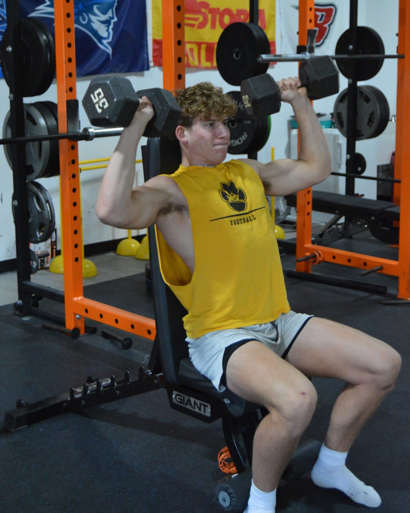 An athlete presses dumbbells overhead during training at Jarosh Performance.