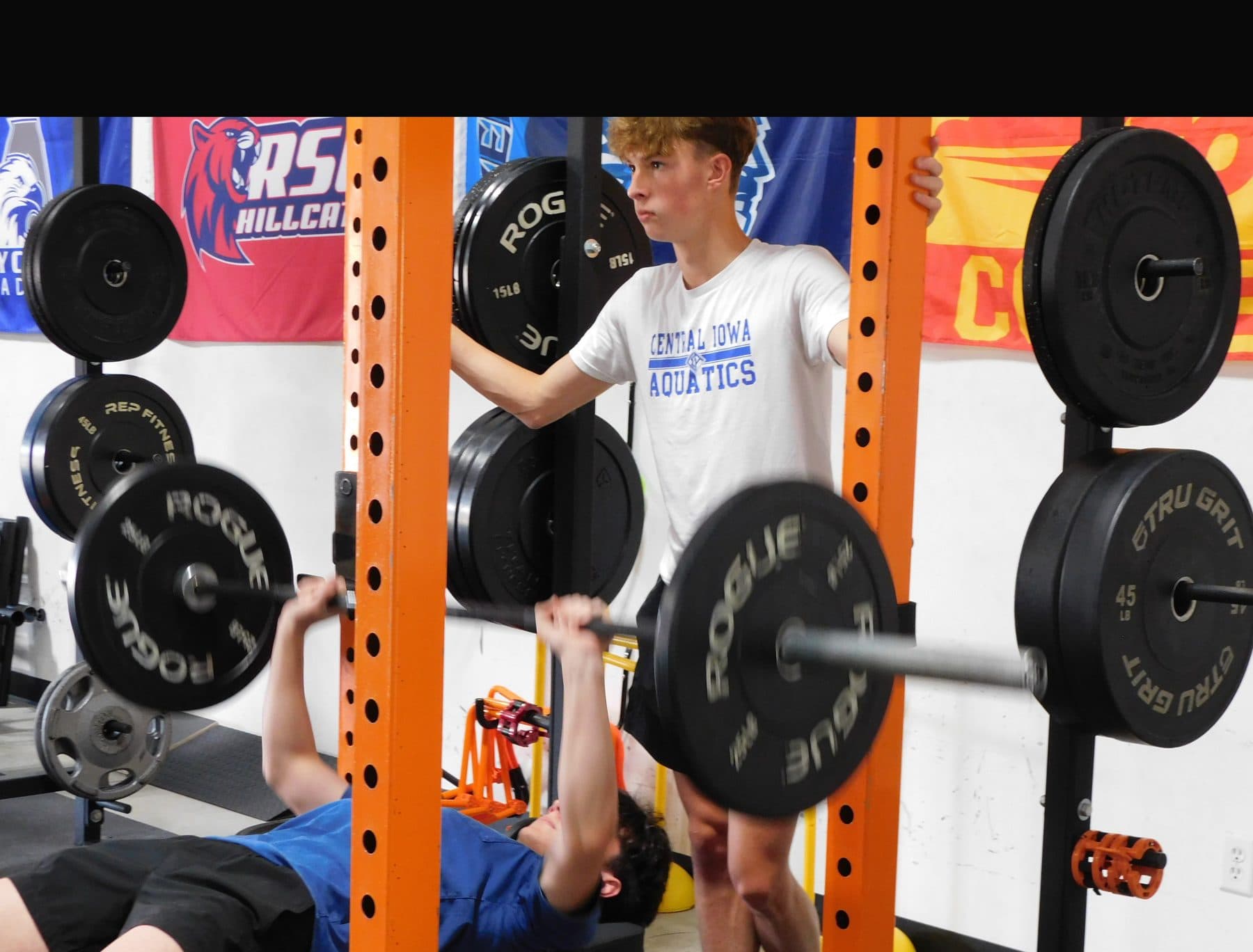 An athlete spots a barbell bench press during training at Jarosh Performance.